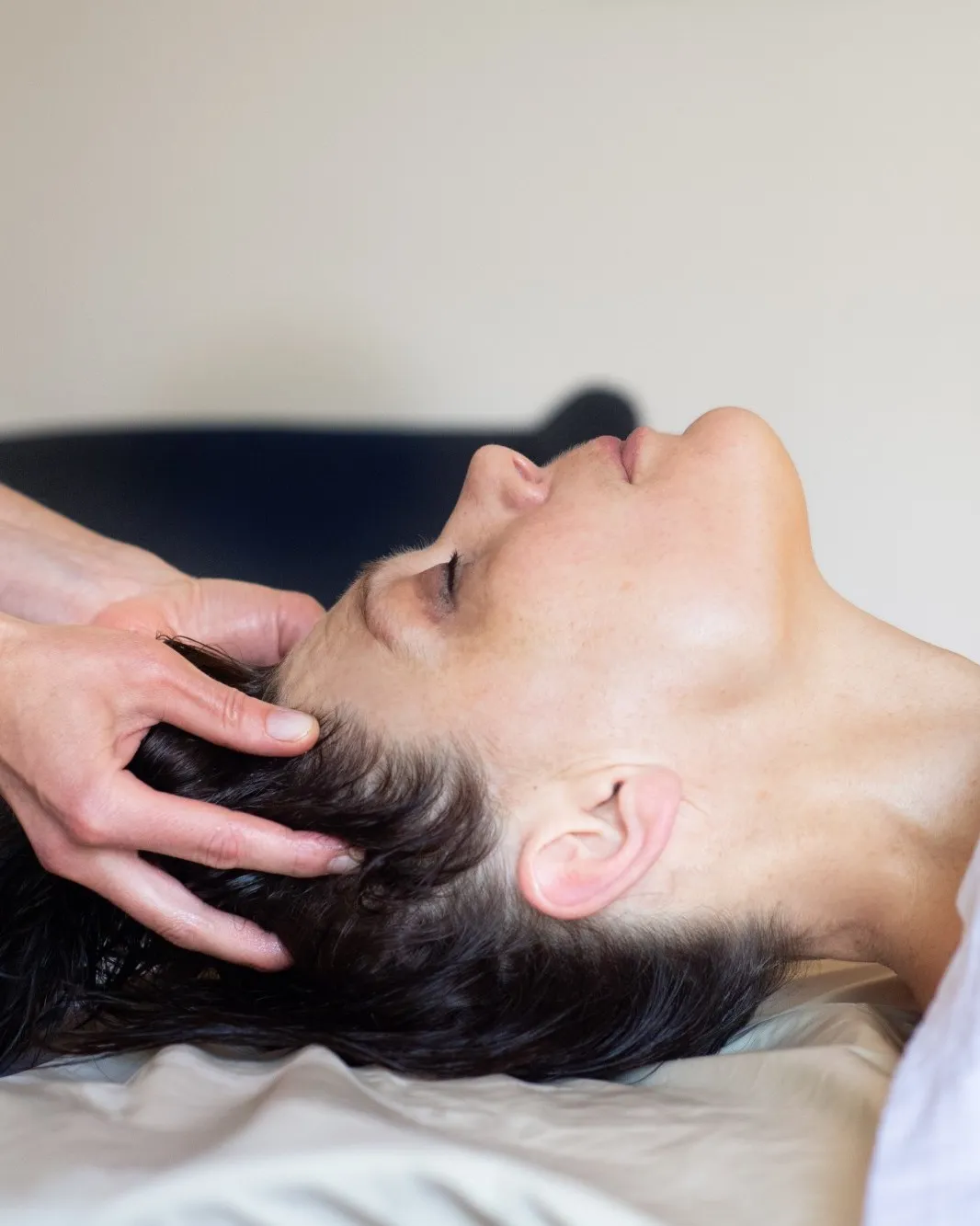Frau liegt entspannt mit geschlossenen Augen, Theresas Hände am Kopf